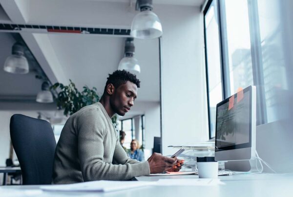Technology Firm Insurance - Male Executive of a Technology Firm Using His Mobile Phone and Troubleshooting with a Client in the Office