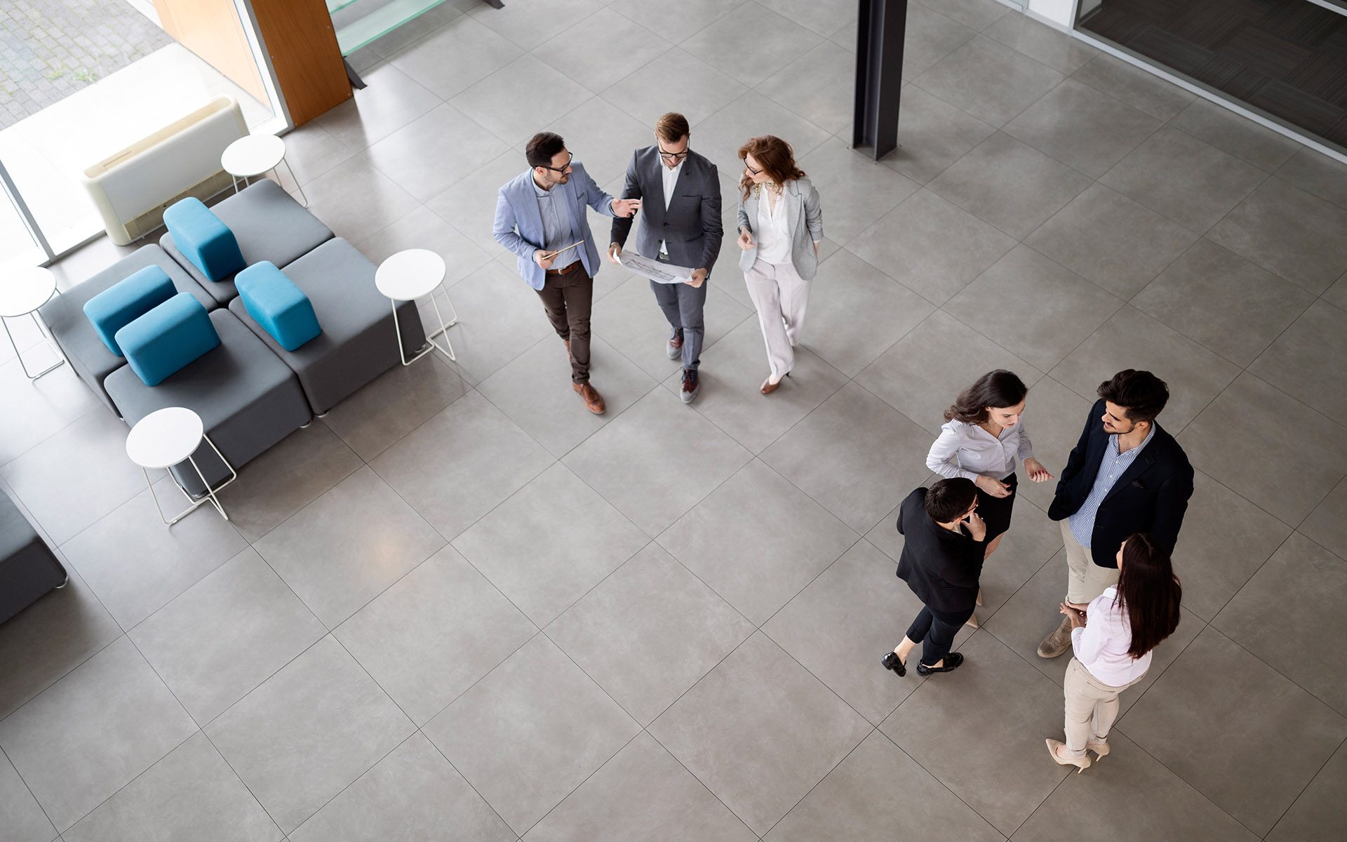 Sweeten Insurance Solutions - Overhead View of a Group of Business Professionals Walking and Talking in the Lobby of a Business Office
